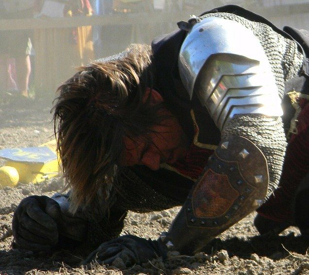 Um soldado medieval no meio de uma encenação de guerra aparentemente ferido. Imagem de jaymethunt por Pixabay