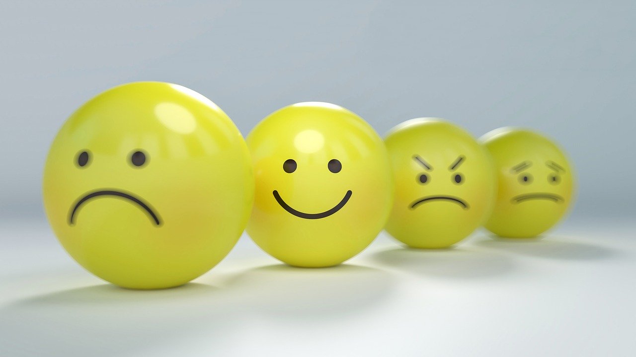 Represetação de emoções humanas. 4 bolinhas amarelas, sendo a primeira com expressão triste, a segunda com uma expressão sorridente, a terceira com um expressão de raiva, e a quarta com uma expressão indiferente. Imagem de Gino Crescoli por Pixabay